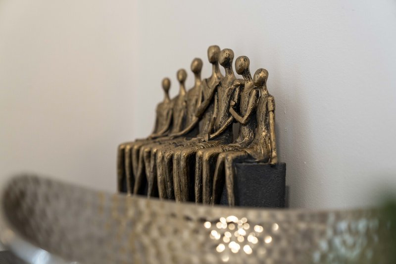 Bronze decorative figurine sculpture with multiple standing figures on display shelf
