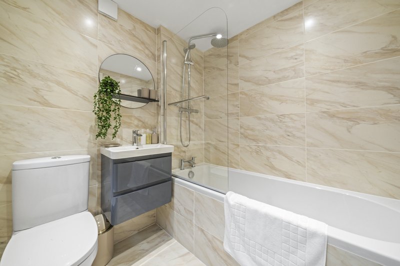 Modern bathroom with marble-effect tiles, vanity sink, toilet, bathtub and shower enclosure