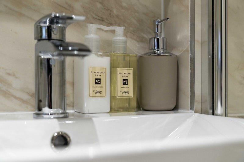 Bathroom sink with chrome tap, soap dispensers and toiletries arranged on counter