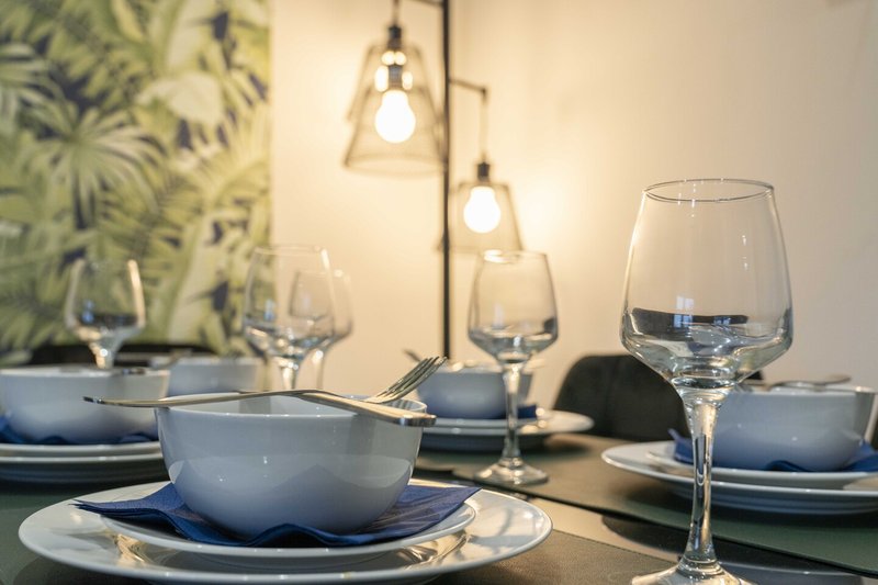 Formal dining table set with blue bowls, plates, glasses and pendant lighting