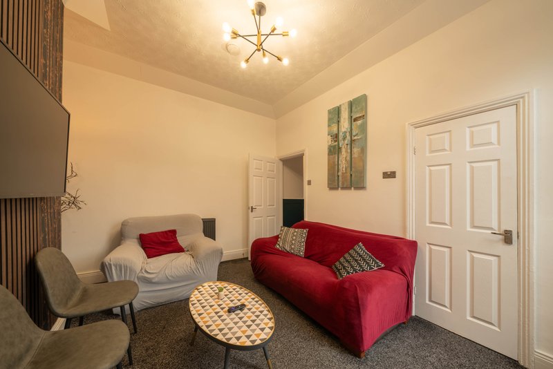 Living room with red sofa, grey armchair, wooden coffee table and wall art