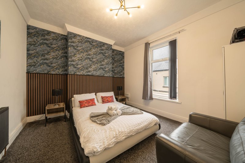 Modern bedroom with double bed, patterned headboard, window and ceiling light fixture