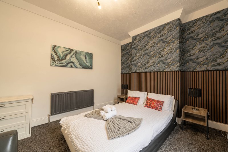 Modern bedroom with double bed, patterned headboard, radiator and contemporary wall art
