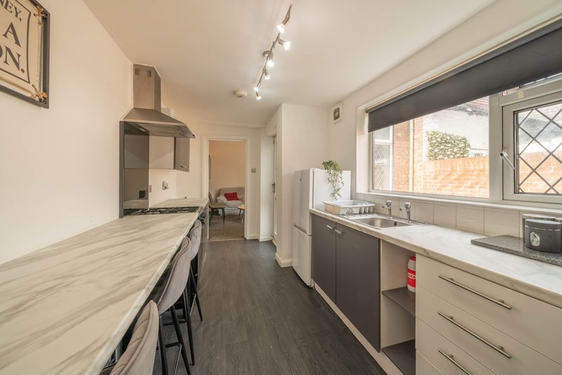 Modern kitchen with light wood countertops, cream cabinets, stainless steel range hood and window