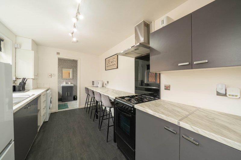 Modern galley kitchen with grey cabinetry, stainless steel appliances and breakfast bar seating