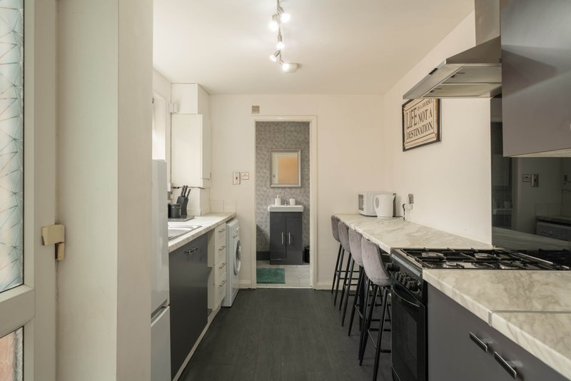 Modern galley kitchen with stainless steel appliances, marble countertops, and dining area