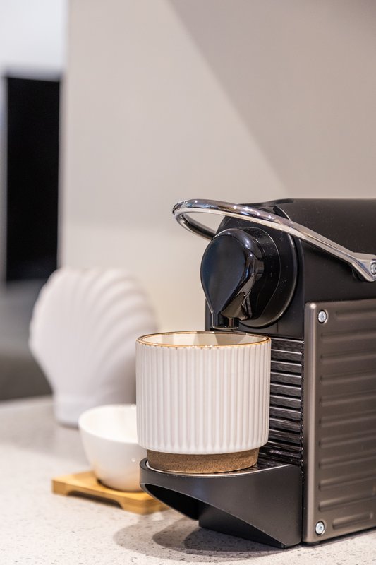 Black and silver coffee machine with white cup on countertop