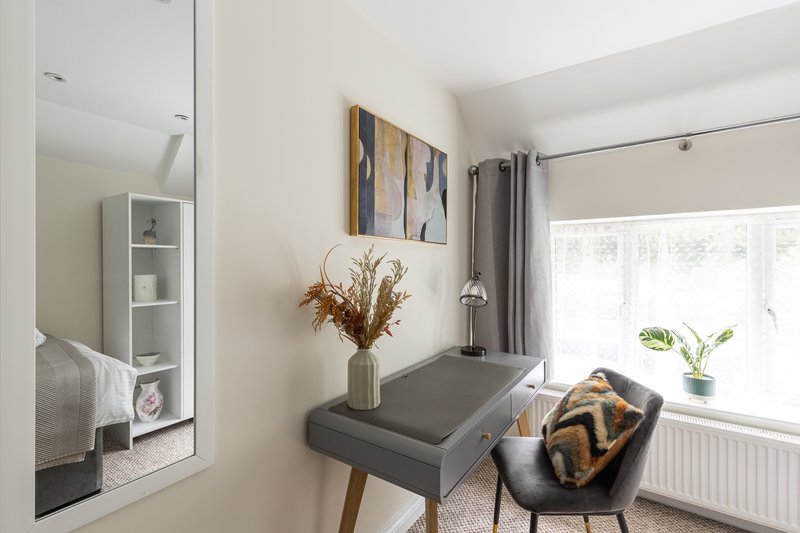Modern home office with desk, chair, window, and decorative wall art