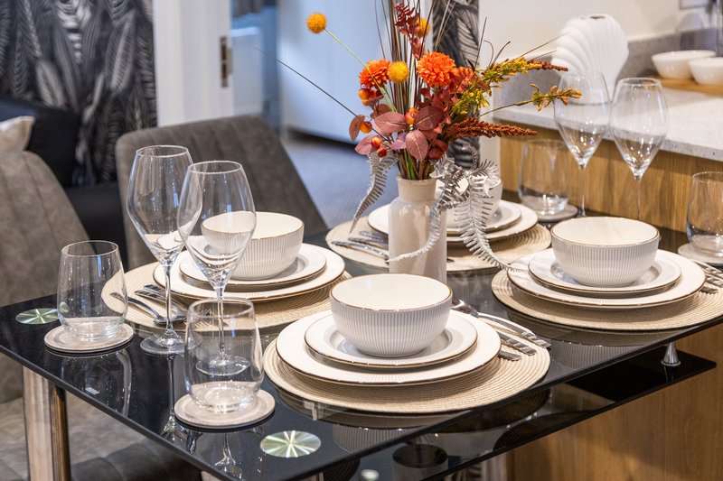 Dining table set with place settings, wine glasses, and orange flower centerpiece