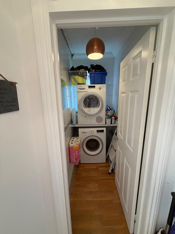 Laundry room with stacked washing machine and tumble dryer along with two free standing airers.