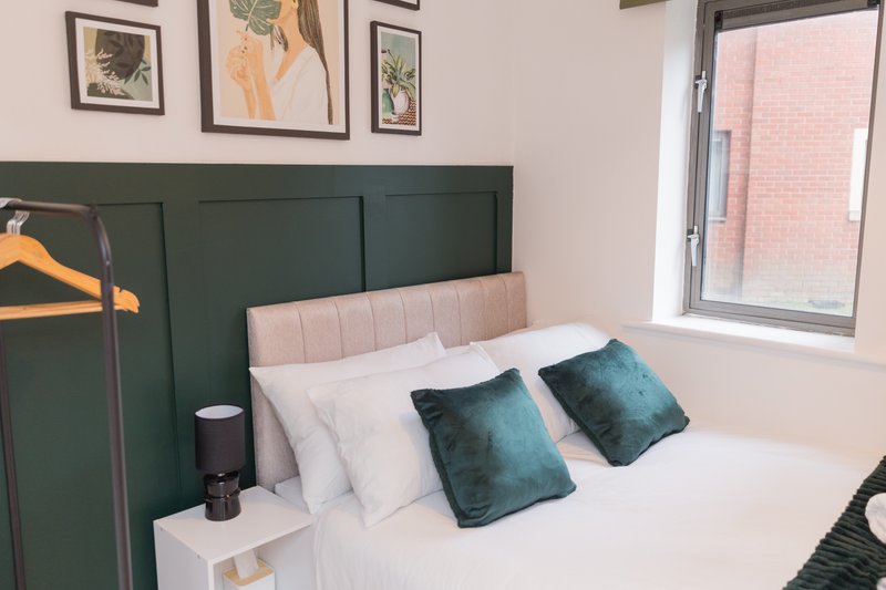 Bedroom with green headboard, pink upholstered bed, teal cushions and white bedding
