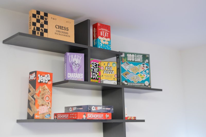 Wall-mounted shelves displaying board games, chess set, and boxed games