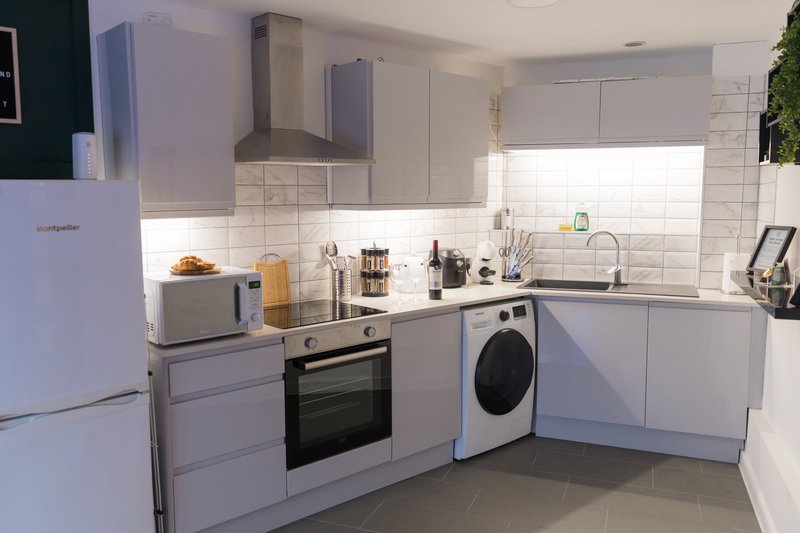 Modern kitchen with white cabinetry, stainless steel appliances, tiled backsplash and window