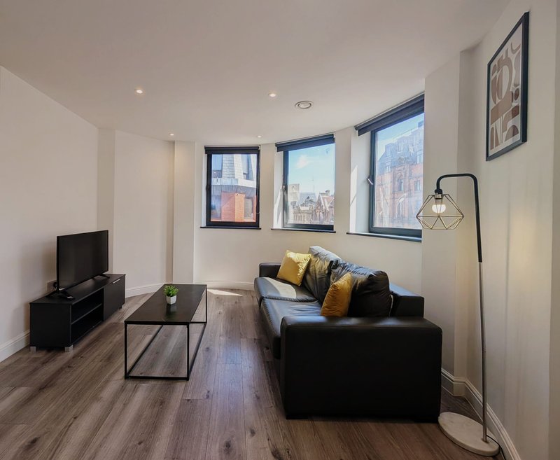 Modern living room with black sofa, TV unit, coffee table and city views from windows