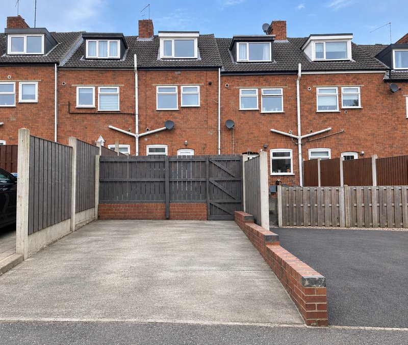 Red brick terraced houses with driveways, gates, and parking area frontage