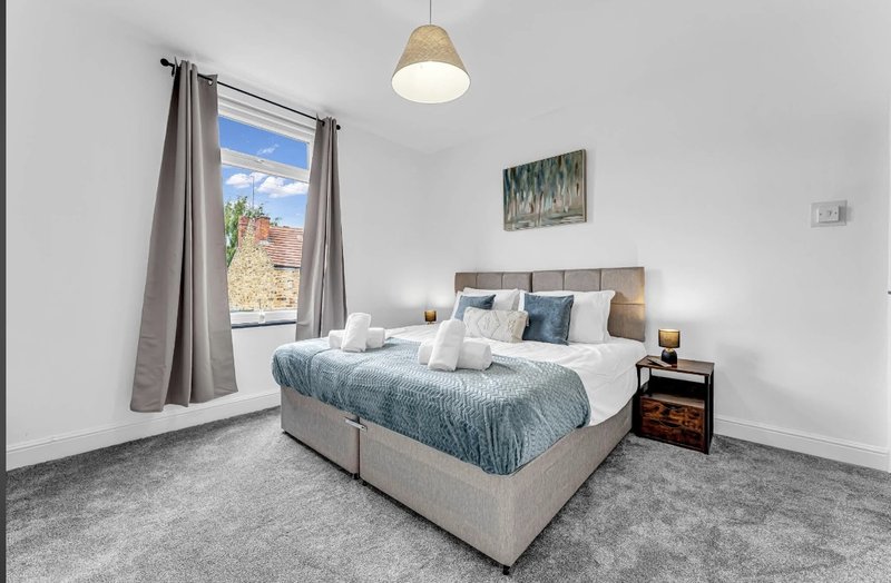 Bright bedroom with queen bed, grey carpet, window with mountain view, pendant light