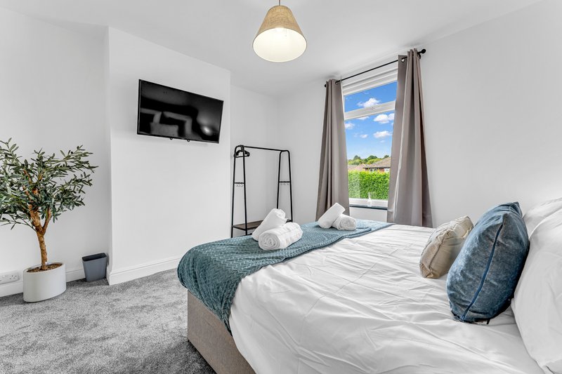 Bright bedroom with two single beds, white bedding, window with rural view, wall-mounted TV and pendant light