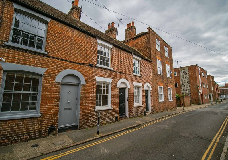Row of traditional brick terraced houses with arched doorways on residential street