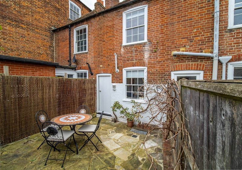 Brick cottage with small paved garden, outdoor dining table and chairs