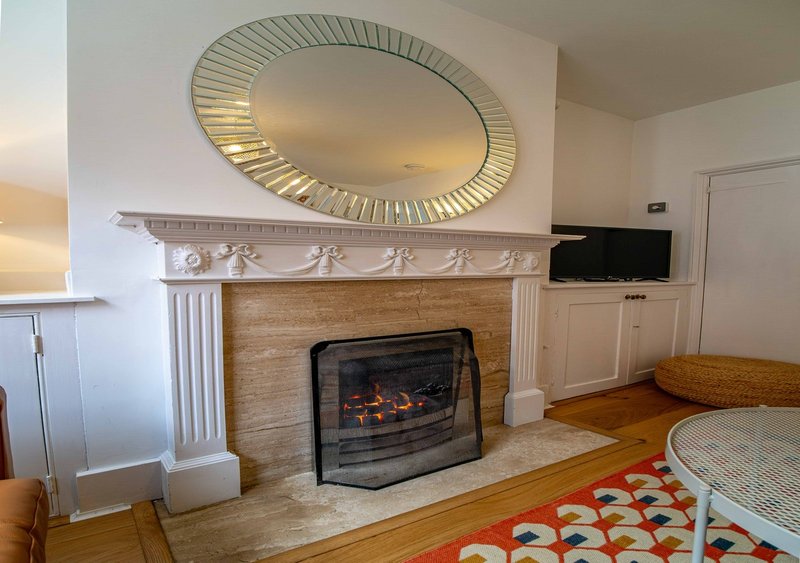 Living room with fireplace, decorative mirror, TV, and colorful patterned rug