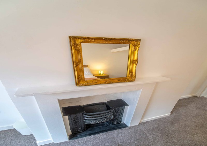 White fireplace mantelpiece with ornate gold-framed mirror and electric fire insert