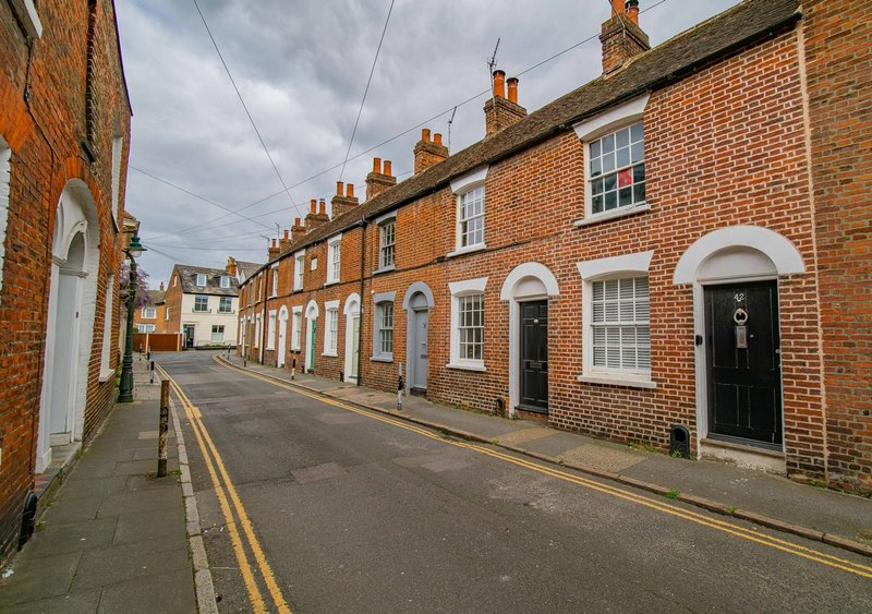 Terraced brick houses with black doors and white sashes on quiet residential street