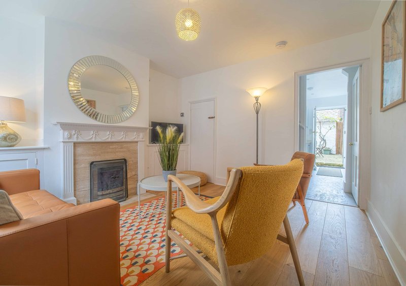 Living room with fireplace, orange armchairs, round mirror and wooden flooring