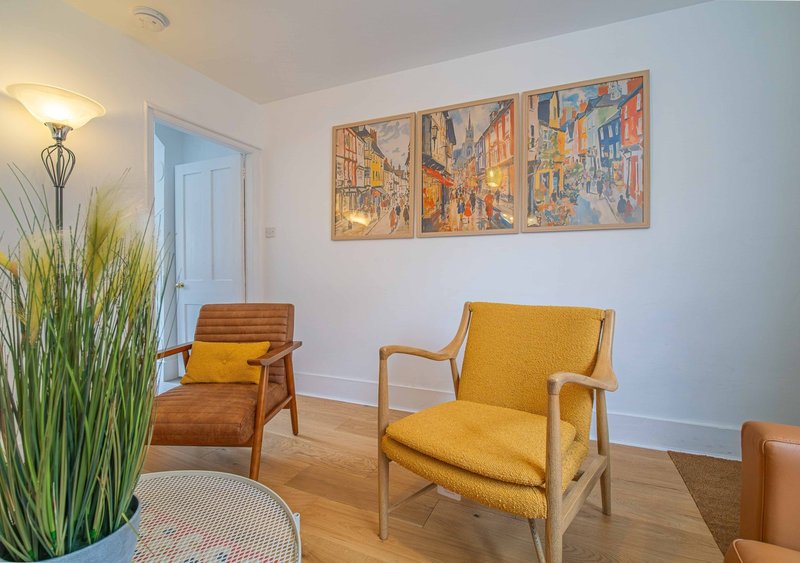 Bright living room with two mid-century armchairs, potted plant, and framed artwork on wall