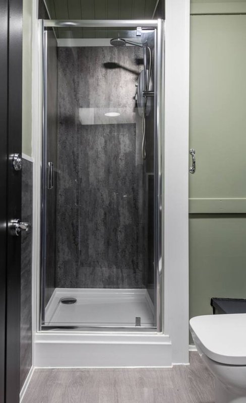 Modern bathroom with enclosed shower cubicle, white toilet and grey vinyl flooring
