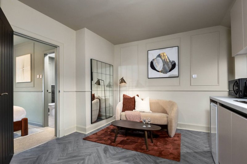 Modern studio apartment with cream sofa, kitchenette, framed wall art and ensuite bathroom