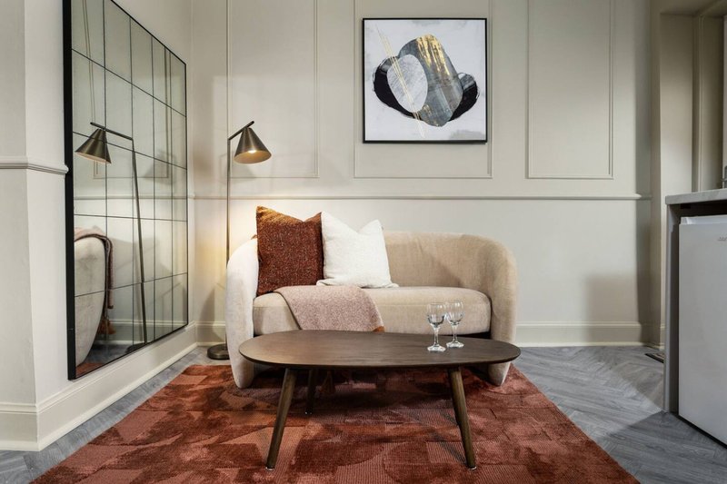 Modern living room with beige sofa, wooden coffee table, rust-colored rug and wall art