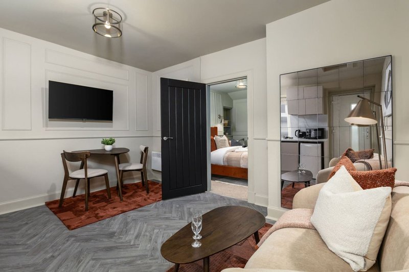 Modern studio apartment with living area, desk, TV, bathroom and bedroom visible through open doors
