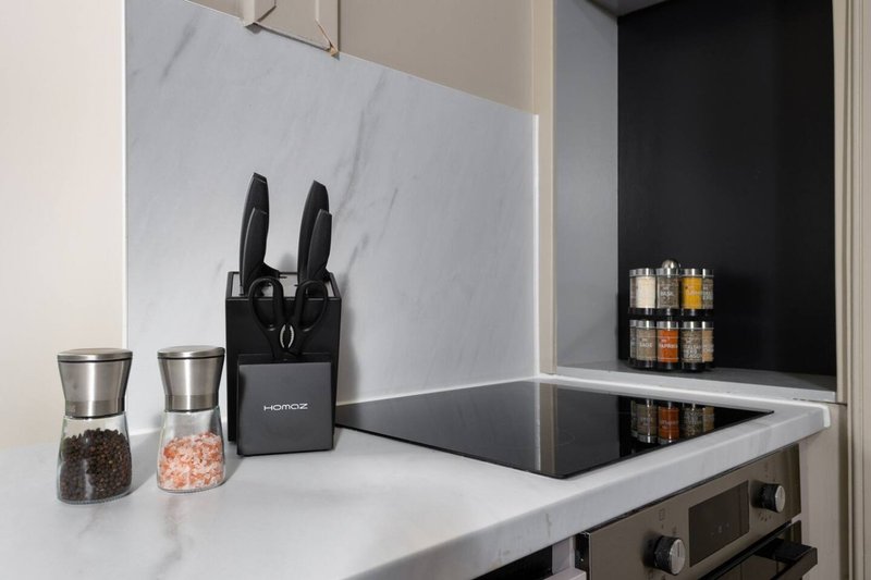 Modern kitchen with white countertop, black knife block, glass jars, and spice rack