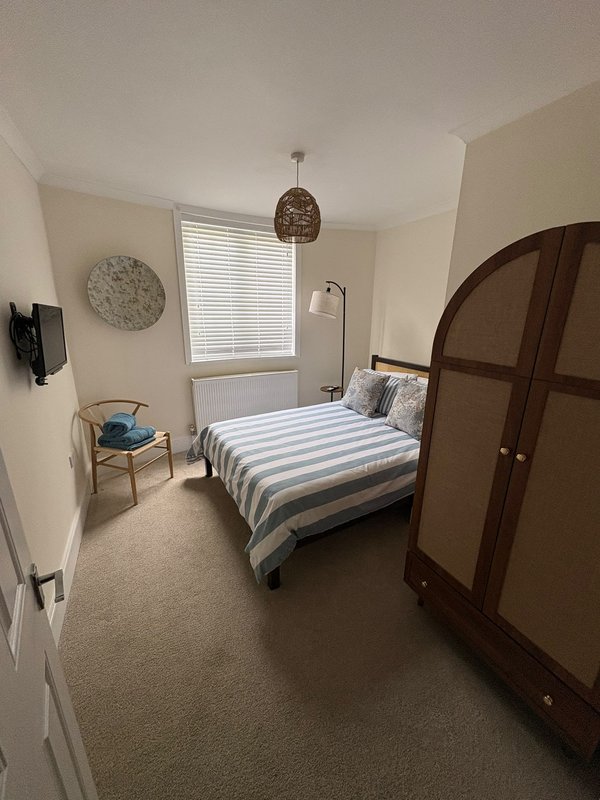 Bedroom with striped bed, wooden wardrobe, pendant lamp, window with blinds