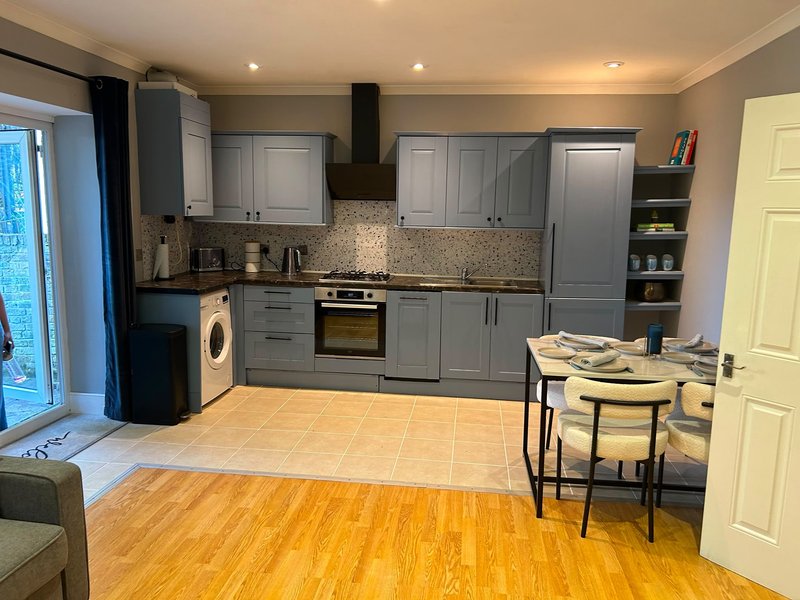 Modern kitchen with gray cabinets, dining table, and wood flooring throughout open-plan space