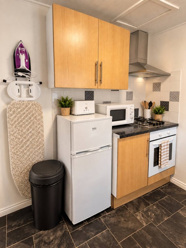 Compact kitchen with white refrigerator, electric range, wooden cabinets and black countertop