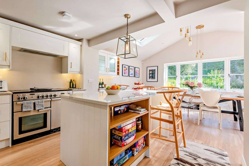 Modern kitchen with white cabinetry, island, wooden dining chairs and large windows