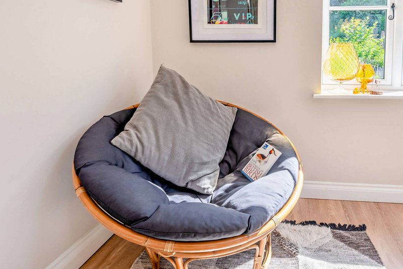 Cozy reading nook with round papasan chair, gray pillow, and window view