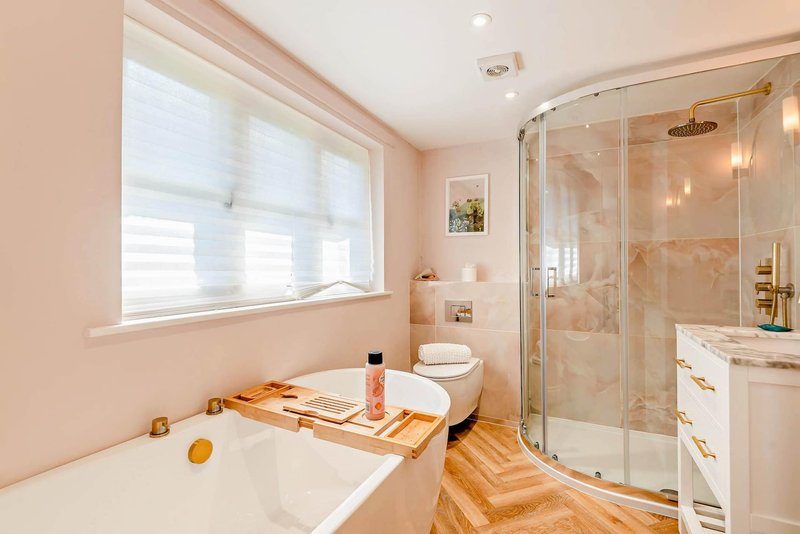 Spacious bathroom with bathtub, shower enclosure, wooden flooring and vanity