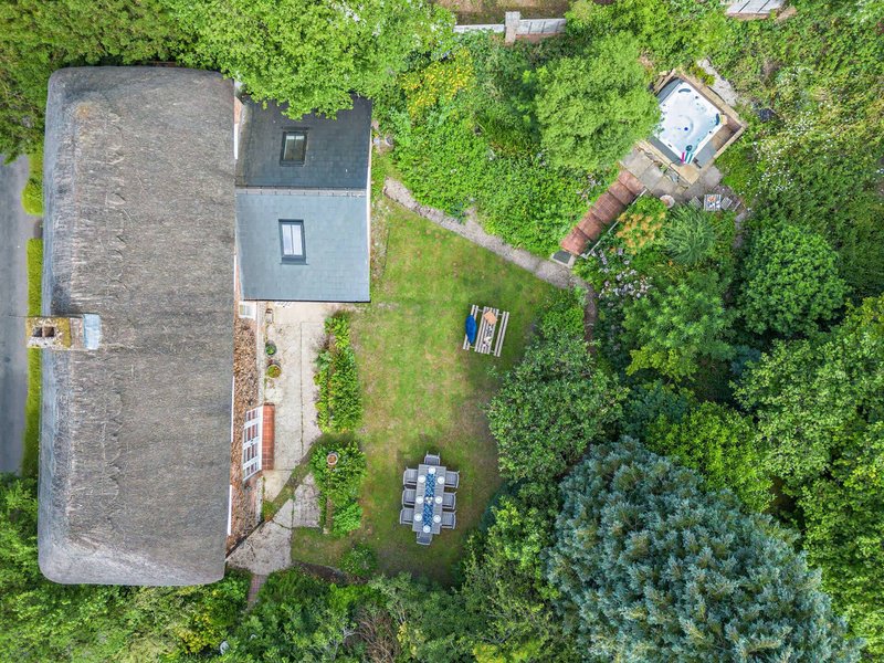 Aerial view of property with slate roof, garden surrounded by trees and woodland