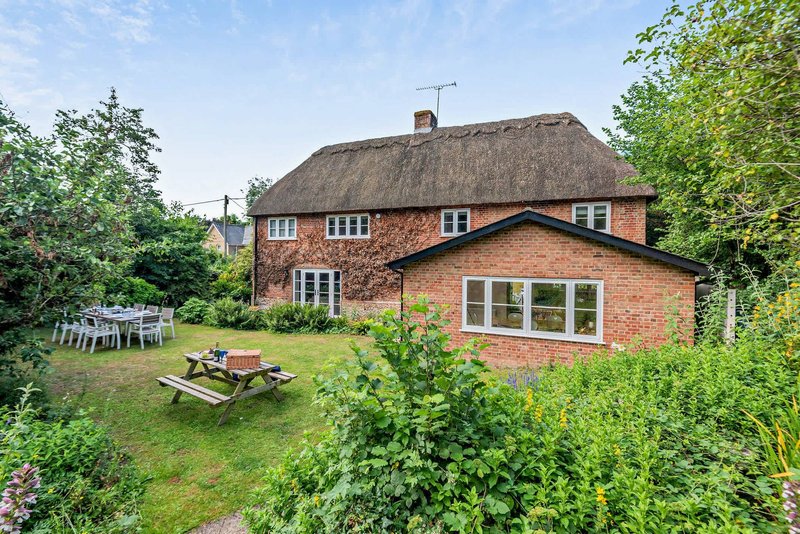 Brick cottage with thatched roof, garden with picnic table and outdoor seating