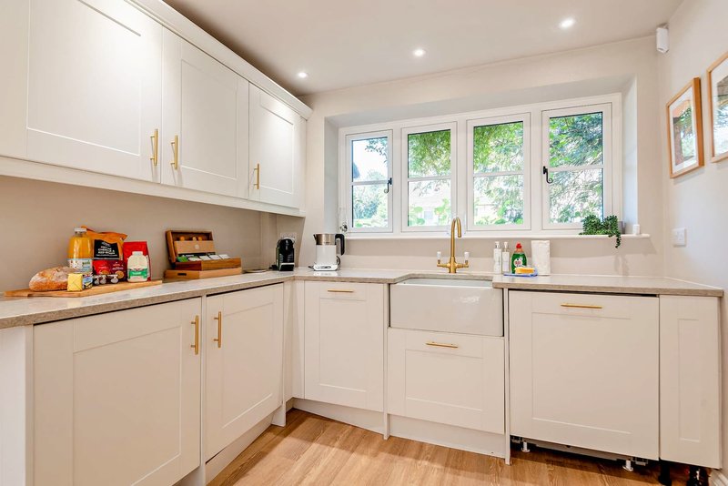 Modern kitchen with white cabinets, wooden countertop, stainless steel appliances and garden views