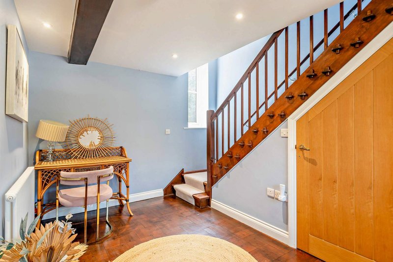 Hallway with wooden staircase, console table with decor, and wood flooring