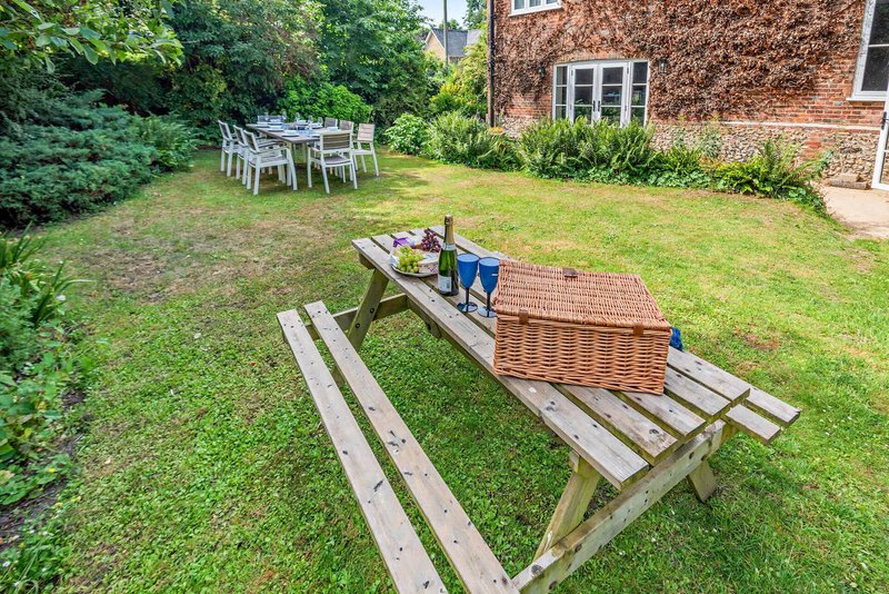Garden with picnic tables, seating area, brick building and green lawn