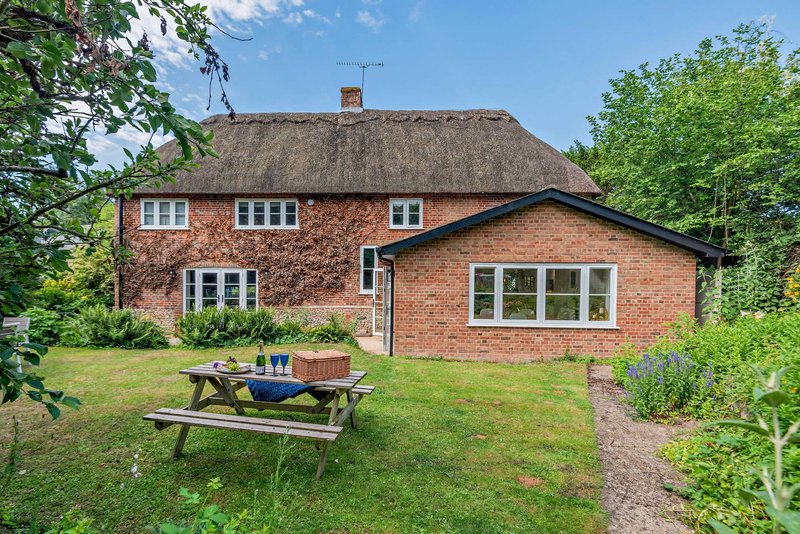 Brick cottage with thatched roof, garden, picnic table and green lawn