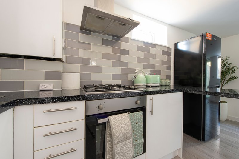 Modern kitchen with white cabinets, black countertop, gas stove and stainless steel appliances