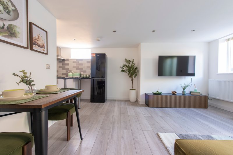 Open-plan living space with dining table, kitchen area, TV, and seating