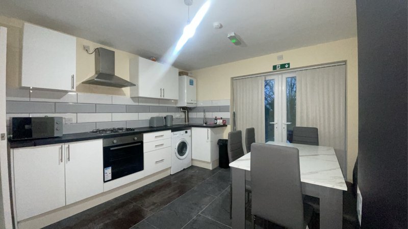 Modern kitchen with white cabinetry, black countertops, dining table and French doors