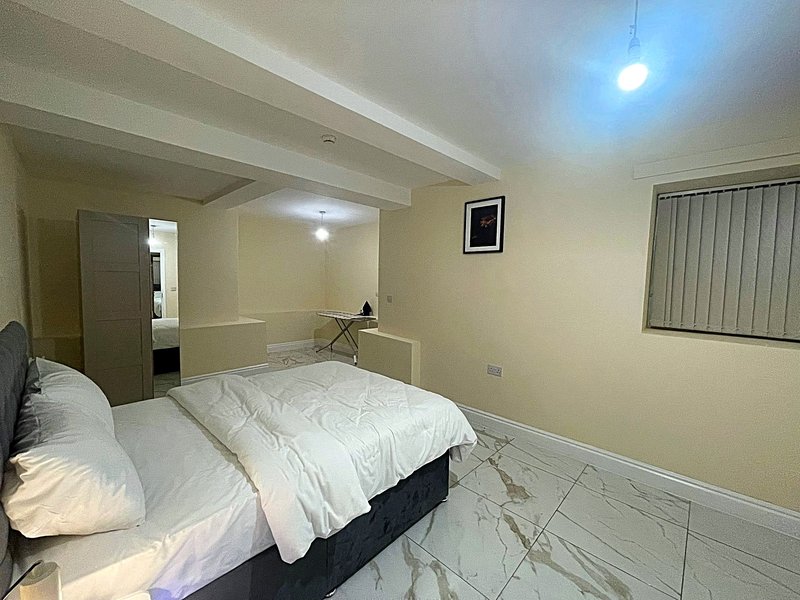 Bedroom with double bed, cream walls, marble flooring and ensuite bathroom entrance