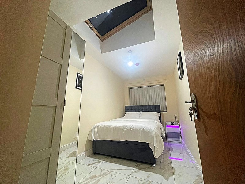 Compact bedroom with double bed, built-in shelving, skylight window and marble flooring